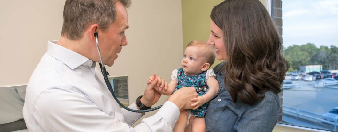 A doctor interacts with a newborn baby and her mother