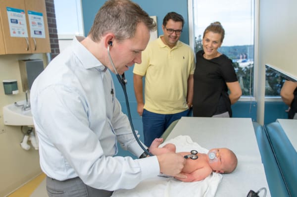 Doctor examines a newborn infant while parents look on