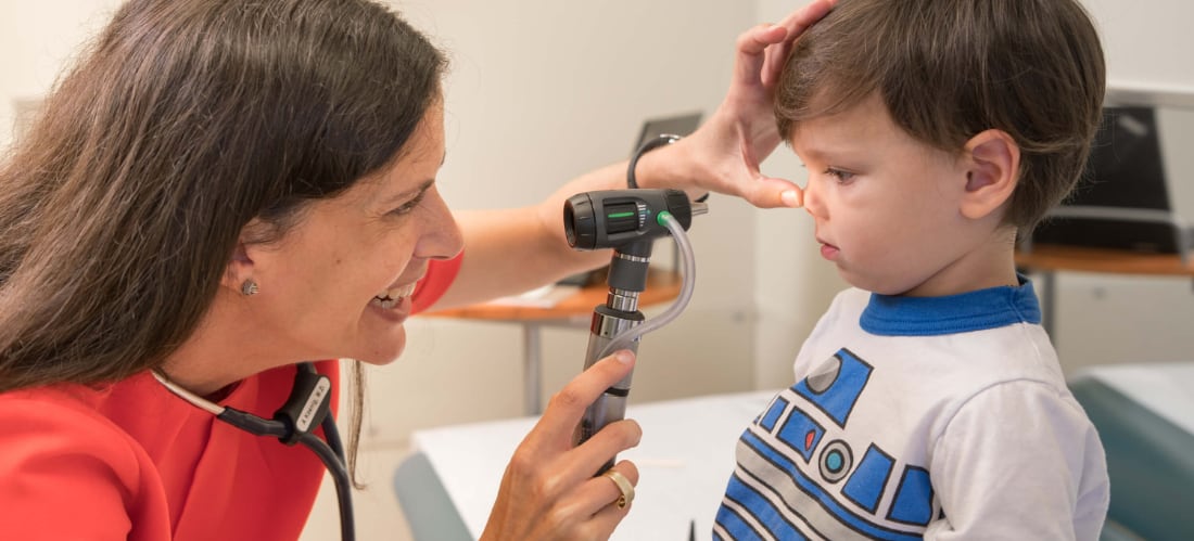 A doctor uses a scope to examine a young boy